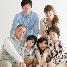 祖父母から孫まで、家族三世代が仲睦まじく寄り添う笑顔の集合写真。