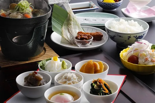 温泉卵やお造りなどの小鉢と温かい小鍋、炊きたてご飯が並ぶ体に優しい朝食和定食