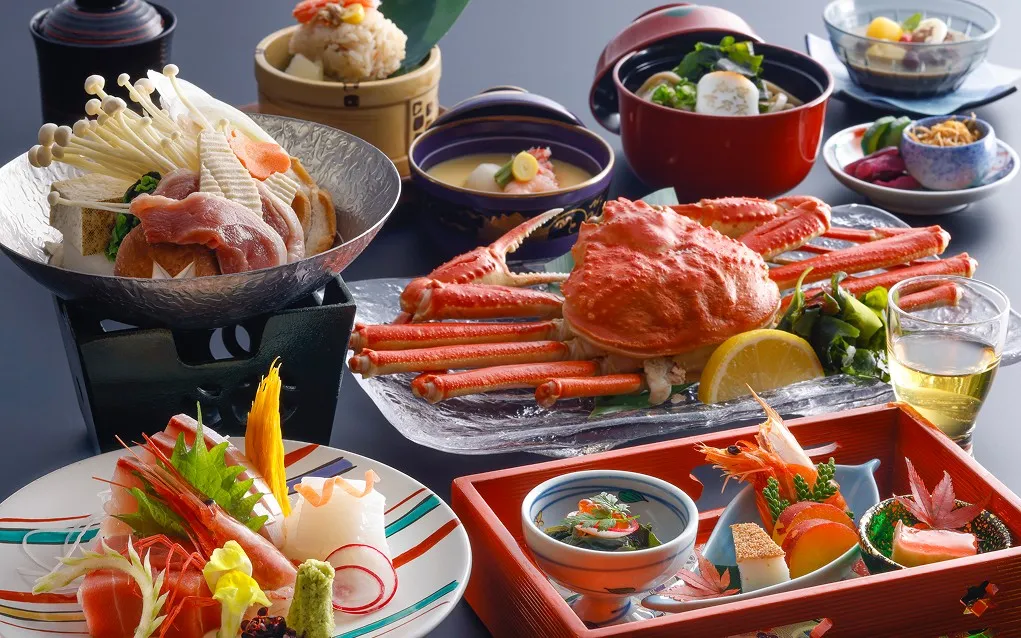 カニや小鍋、新鮮なお造りが美しく並ぶ贅沢な会席料理一式