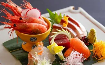 黄色の小鉢に盛られたエビと、数種類の刺身が並ぶ華やかな一皿