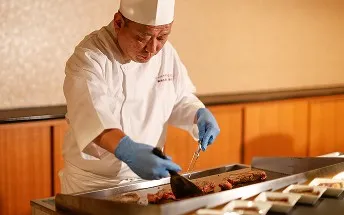 鉄板の上で肉を焼き上げる料理人。