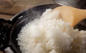 土鍋の中でふっくらと輝く炊きたてのご飯。白い湯気が立ち上る様子。