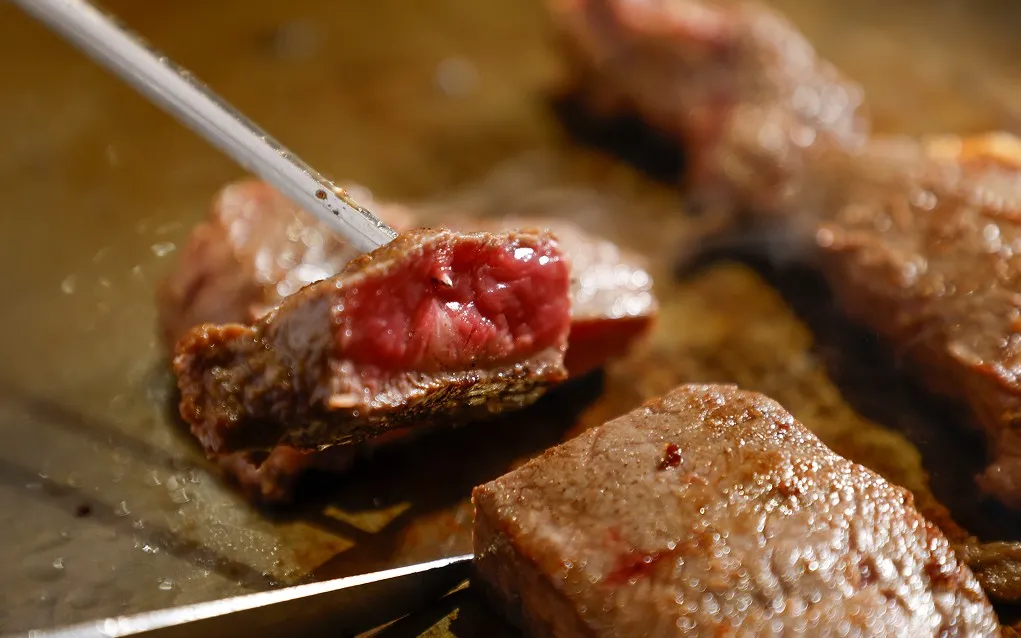 熱い鉄板の上で表面を香ばしく焼き上げ、ジューシーな赤身が覗く厚切りの和牛ステーキ。