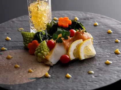 シックな黒いプレートに映える、鮮やかな季節の温野菜と魚介の前菜盛り合わせ。