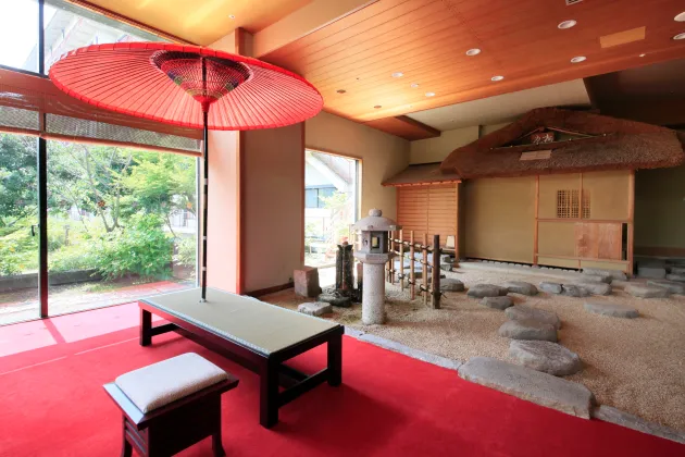赤い和傘と畳ベンチが置かれた東屋風の茶室