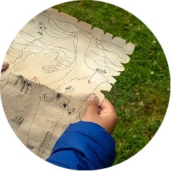 古びた宝地図のようなデザインのマップを広げ、冒険に胸を躍らせる子供の手元の様子。