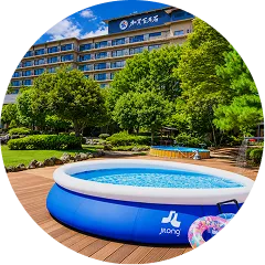 青空のもと、ホテルの庭園のウッドデッキに設置された大きな家庭用ビニールプールと浮き輪。