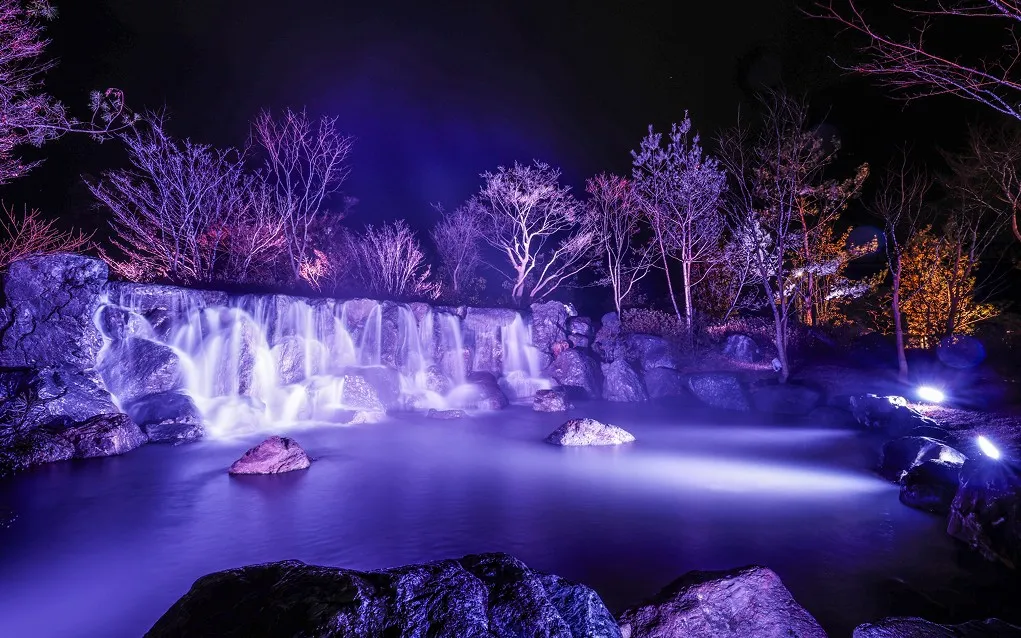 白と紫の幻想的な光に照らし出される夜の美しい滝の景観
