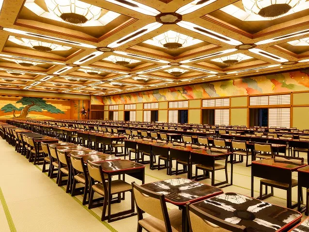 華やかな天井照明と松の壁画がある、畳敷きの大きな宴会場。