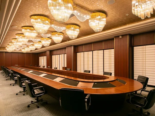 豪華なシャンデリアと大きな楕円形テーブルがある会議室。
