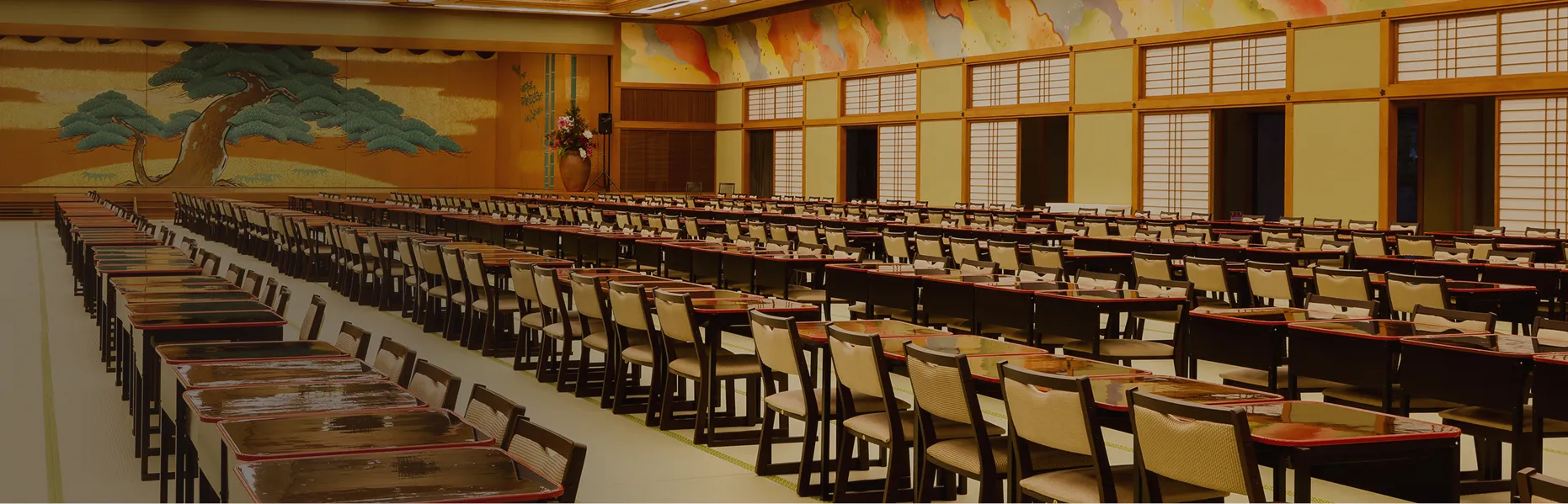 伝統的な松の舞台絵が目を引く、大人数での食事や宴会が可能な舞台付きの畳の広間。