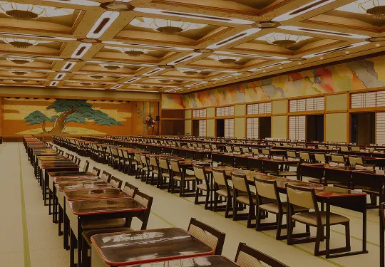 伝統的な松の舞台絵が目を引く、大人数での食事や宴会が可能な舞台付きの畳の広間。