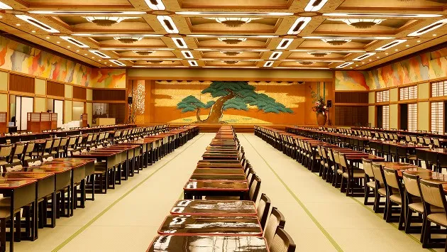 奥まで見渡せないほど広い畳敷きの大宴会場。正面には見事な松の木が描かれた舞台があり、何百もの漆塗りの膳と椅子が整然と並んでいます。
