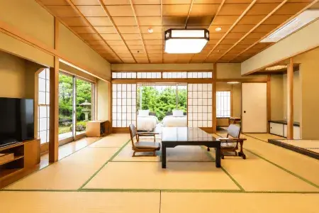 畳敷きの和室に座卓と座椅子、障子戸の奥にツインベッドと庭園を望む客室全景。