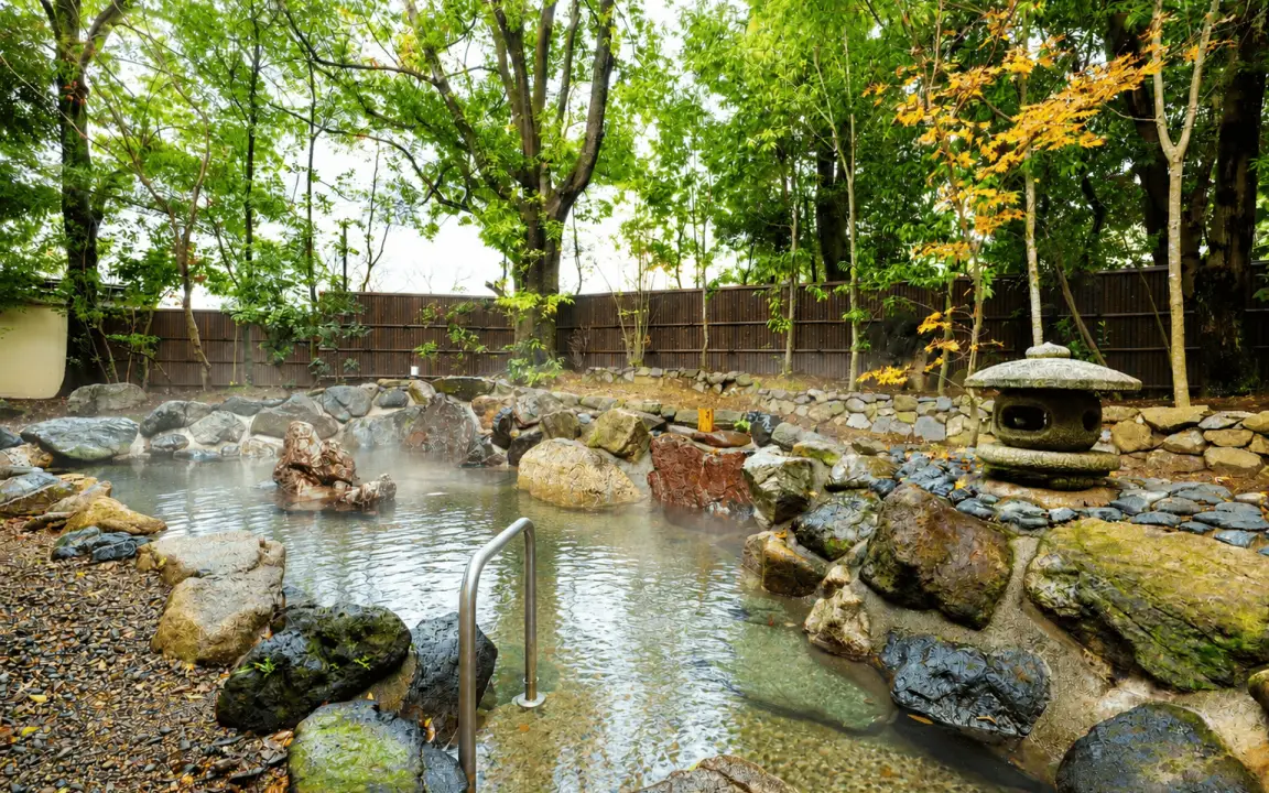 石灯籠と豊かな木々に囲まれた、情緒豊かな別邸の岩露天風呂の風景。